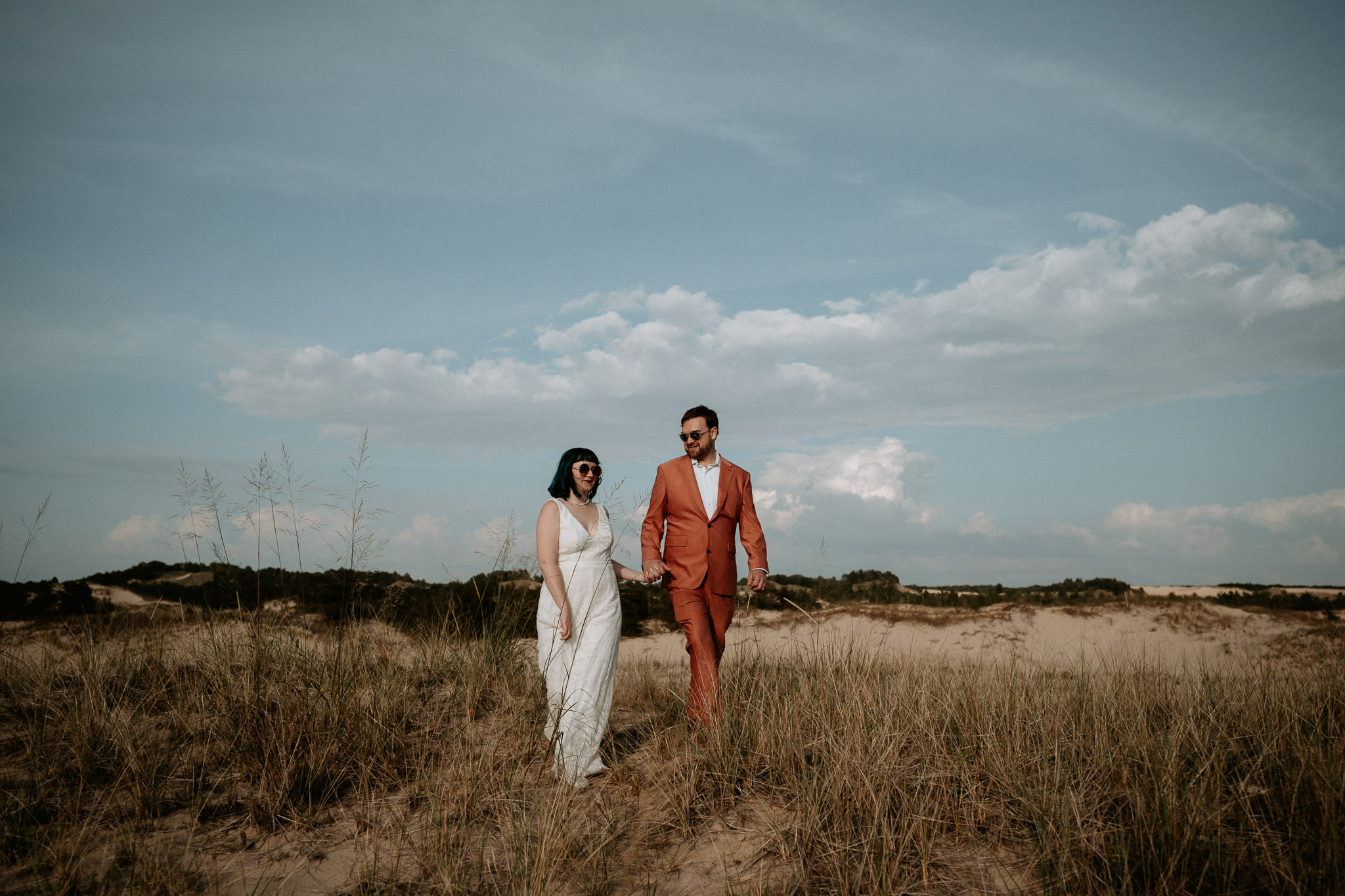 A couple who chose to elope in Michigan at Ludington State park walk over the dunes.