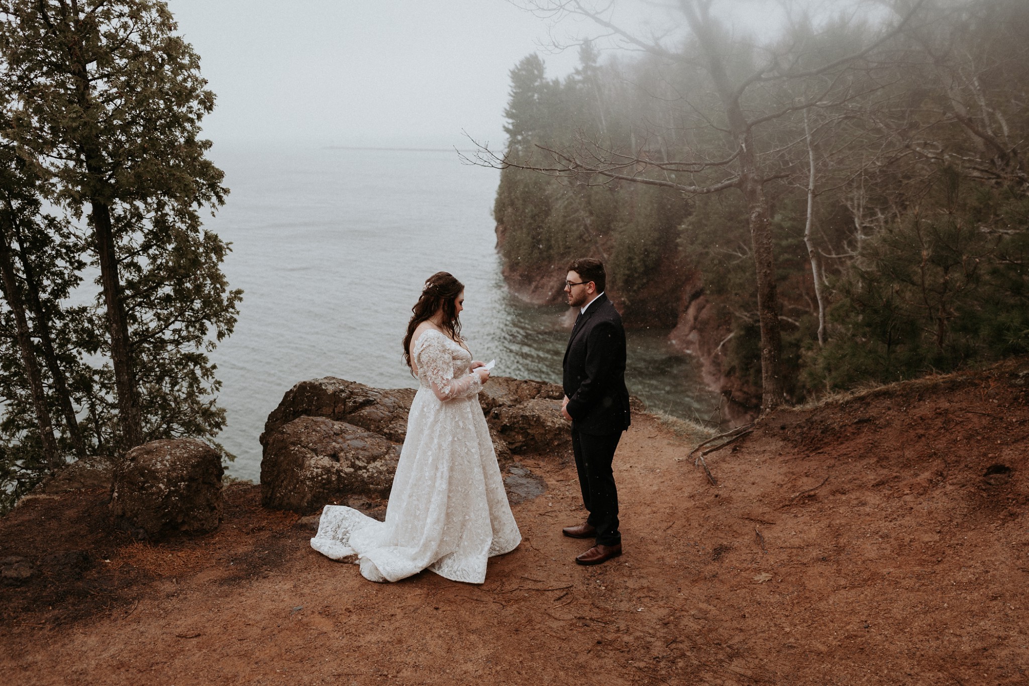 Couple reading wedding vows on a cliff above Lake Superior on Presque Isle, Marquette Michigan.